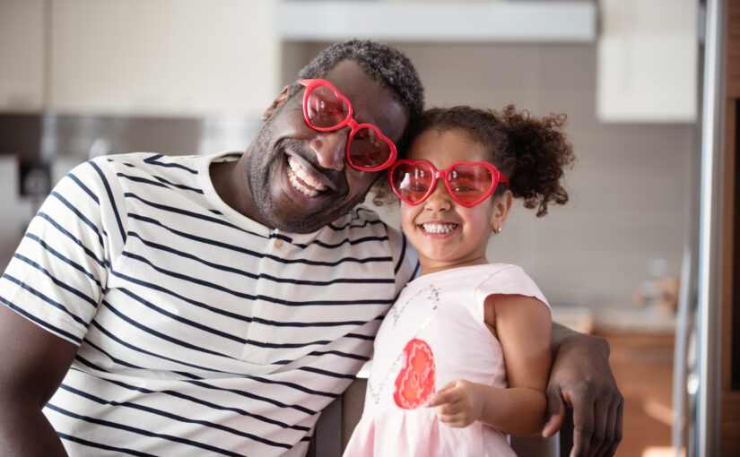 African-American father and daughter wearing Valentine heart sunglasses