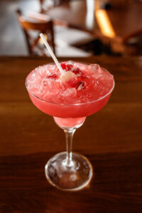 Red cocktail with candy and lollipop at the bar