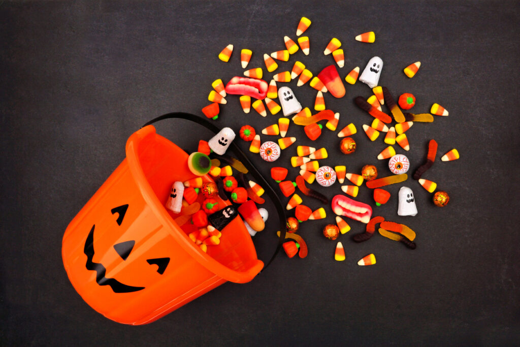 Jack o Lantern pail spilling candy corn, mellowcreme pumpkins, and other Halloween candy
