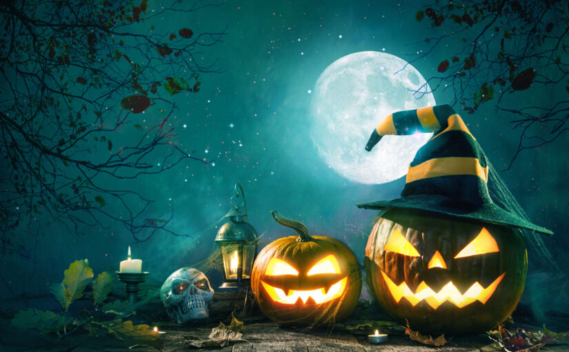 Halloween scene: pumpkin jack o'lanterns, one wearing witch hat, skull and burning candles