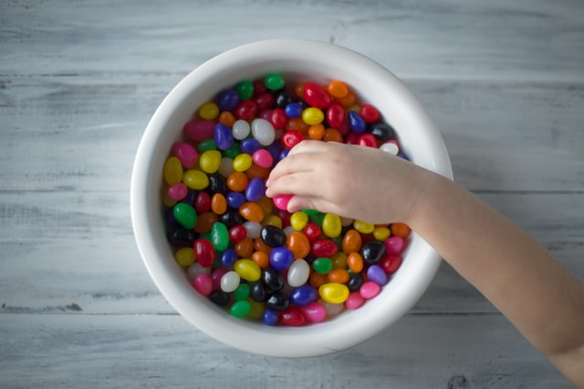 child's hand reaching into bowl of jelly beans