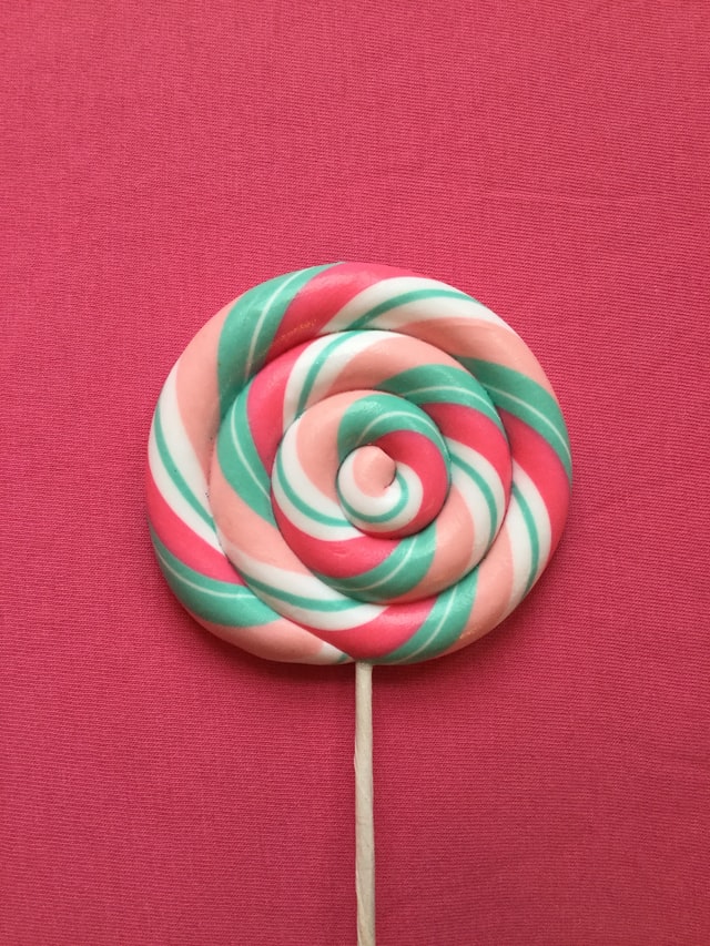 large swirled lollipop against dark pink background