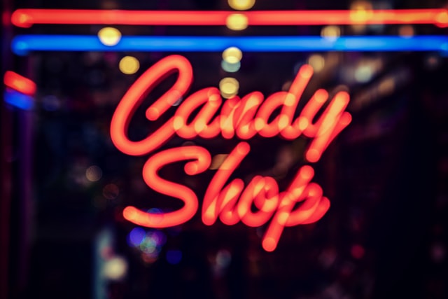 out of focus red and blue neon sign reading "Candy Shop"